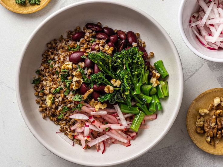 a white bowl filled with lots of food on top of a table next to other bowls