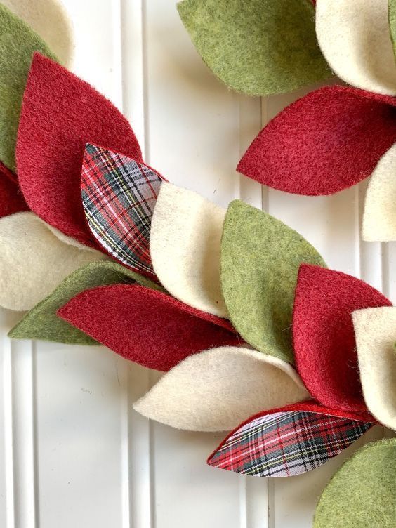 a wreath made out of felt with red, green and white leaves on top of it