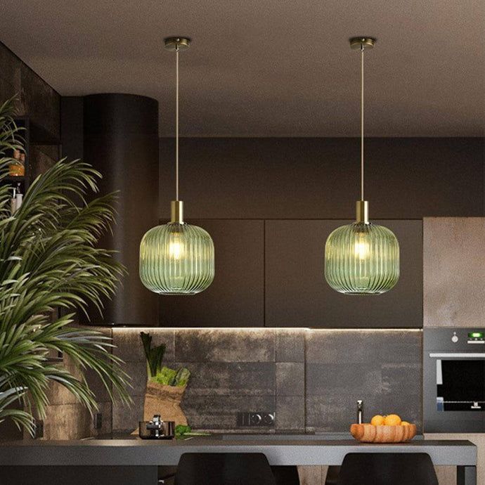 three lights hanging over a kitchen island with black chairs and counter tops, surrounded by potted plants