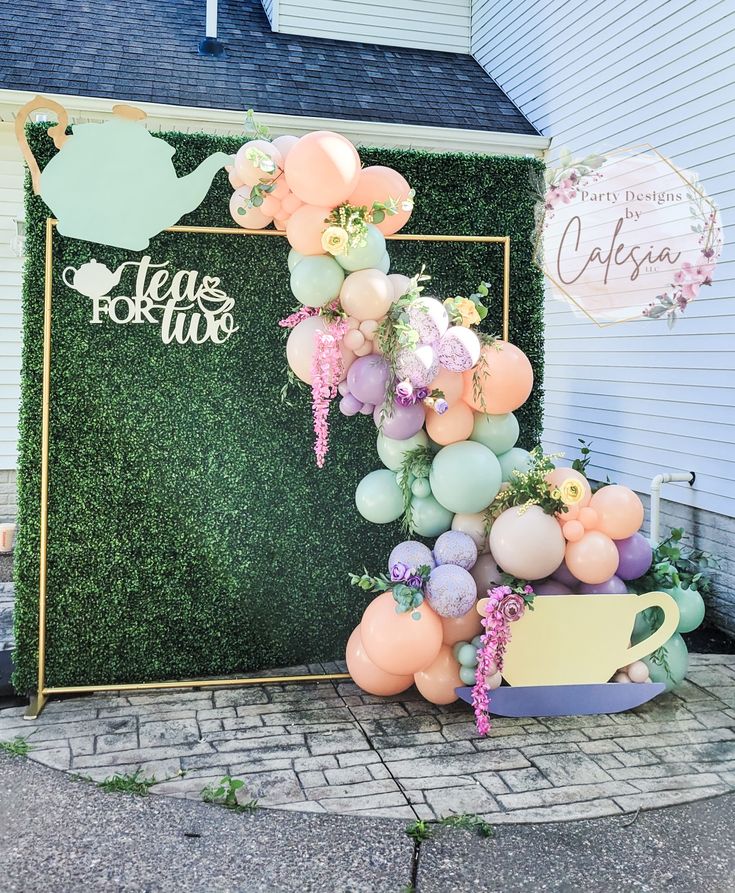 there is a large balloon arch in the shape of a watering can with flowers on it