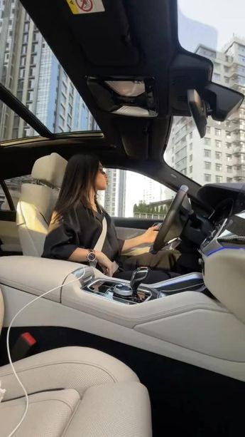 a woman sitting in the driver's seat of a car with headphones on