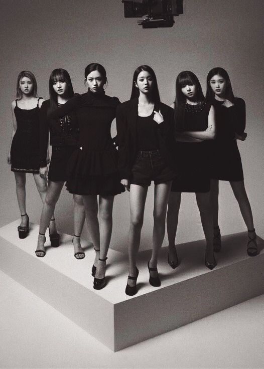 black and white photograph of five women standing on top of a platform with one woman's legs crossed