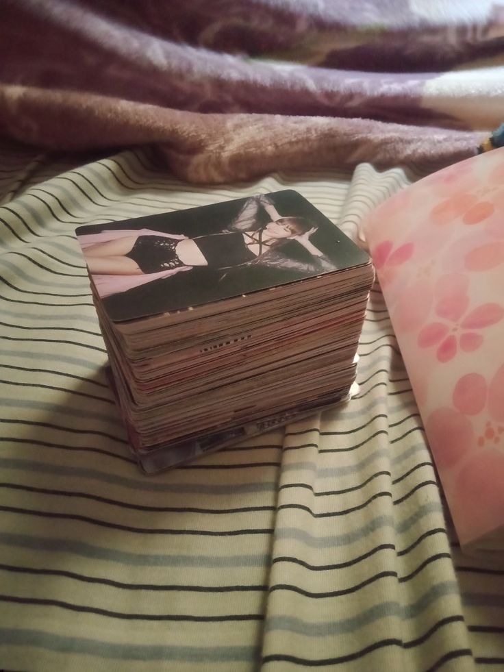 a stack of books sitting on top of a bed next to a pink and white pillow