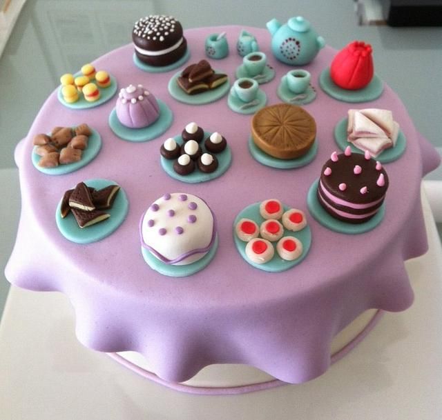 a purple cake topped with lots of different types of cakes