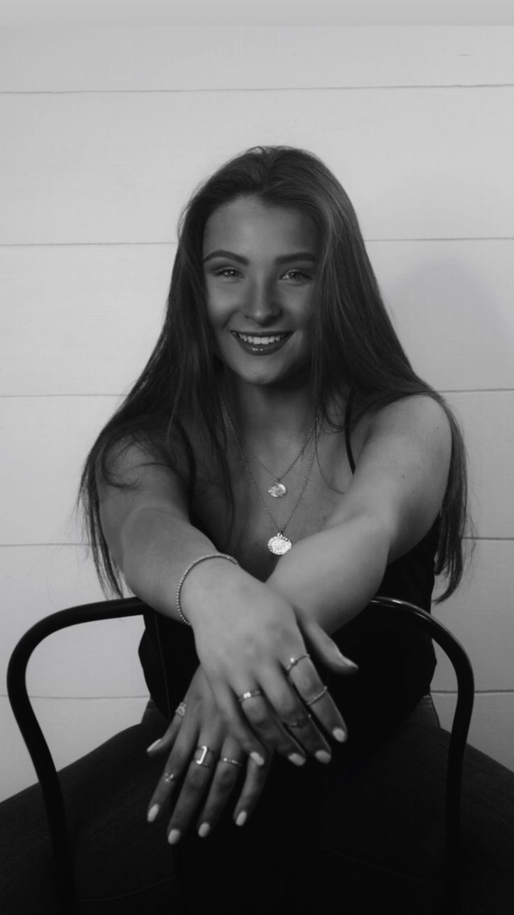 a black and white photo of a woman sitting in a chair with her arms crossed