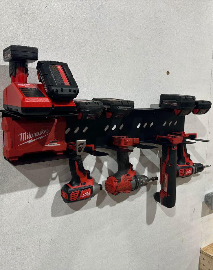 a red and black tool rack mounted to the side of a wall with tools on it