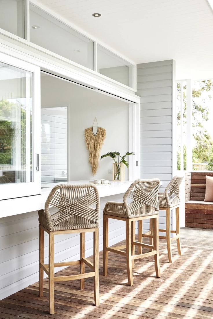 three wicker bar stools sitting on top of a wooden floor next to a white counter