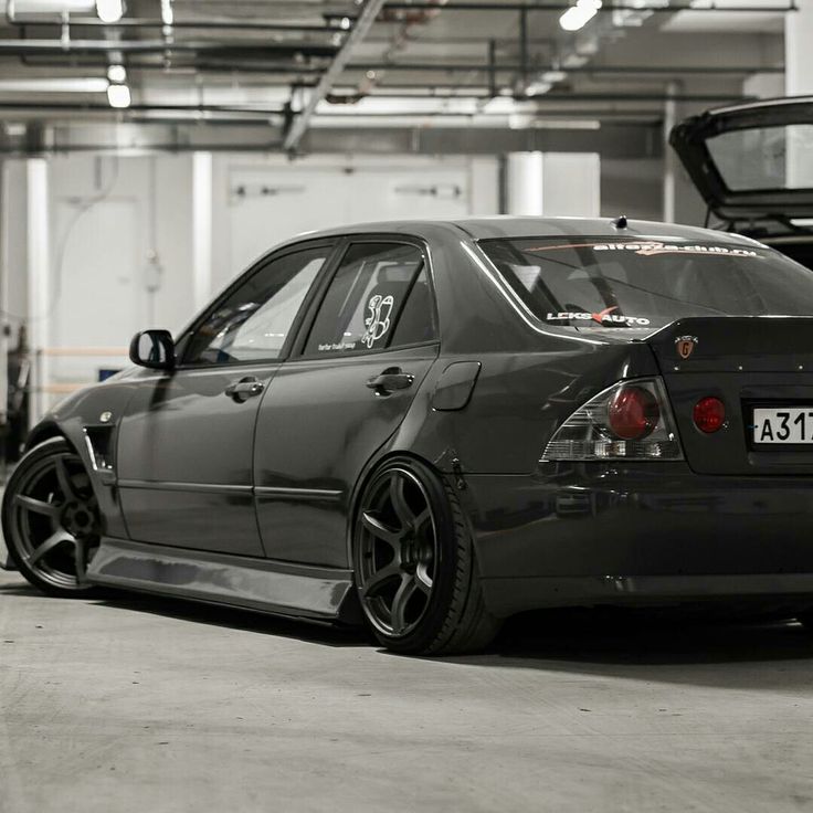 a black car parked in a garage with its hood up and the back end open