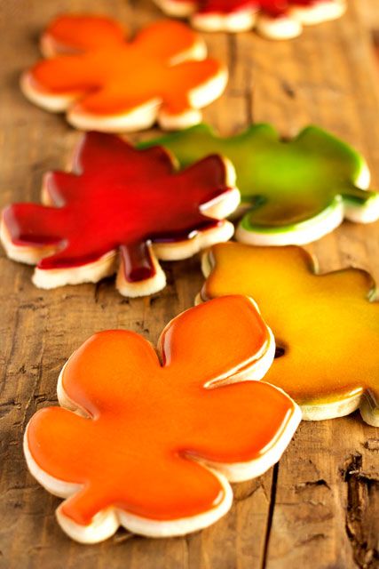 four different colored cookies sitting on top of a wooden table