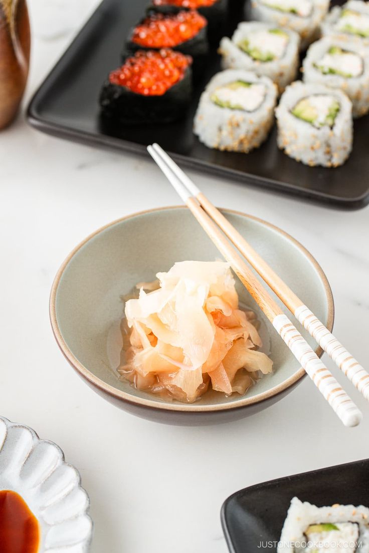 sushi and chopsticks are on the table next to plates with different foods