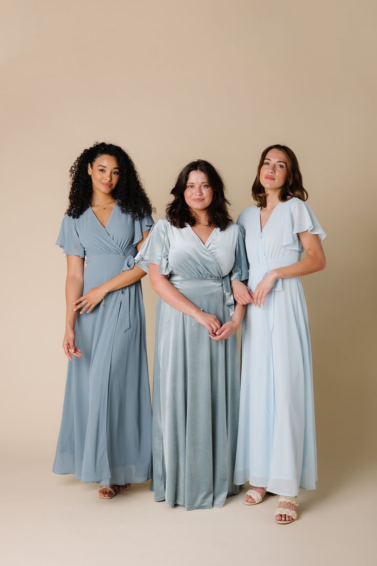 three women in blue dresses posing for the camera with their hands on their hipss