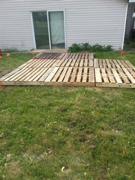 a wooden pallet sitting in the grass near a house