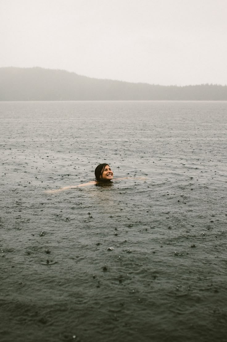 a person floating in the water on top of a body of water with mountains in the background