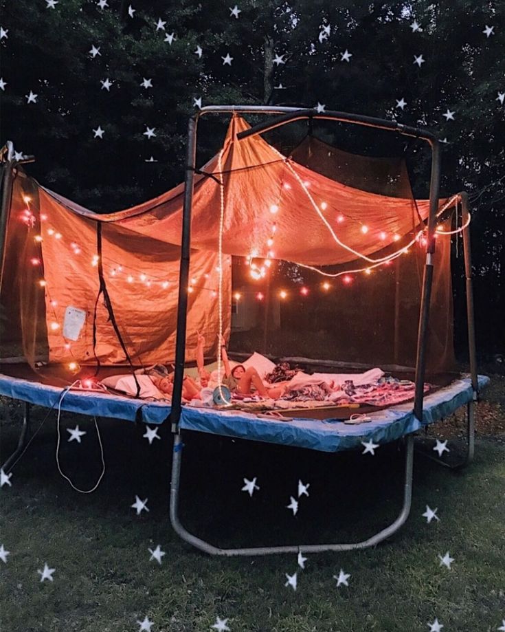 an outdoor trampoline with lights and stars on the ground