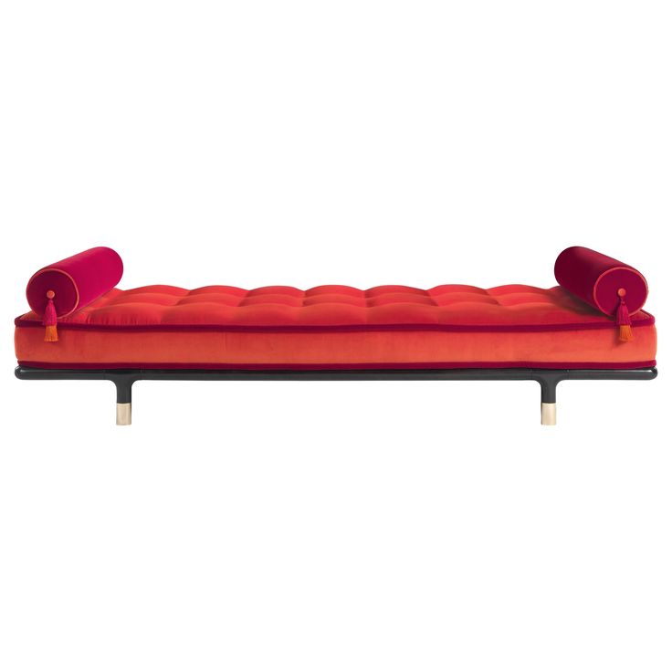 a red couch with two pillows on it's back and one arm extended to the side