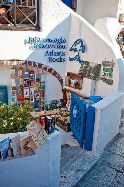 an outdoor book store with blue doors and shelves full of books on the outside wall