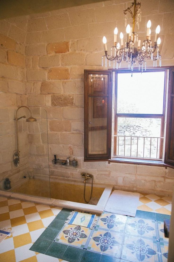 a bath room with a tub a window and a chandelier in it's corner