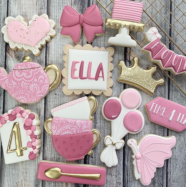 pink and white decorated cookies with gold trimmings on a wooden table next to other decorations