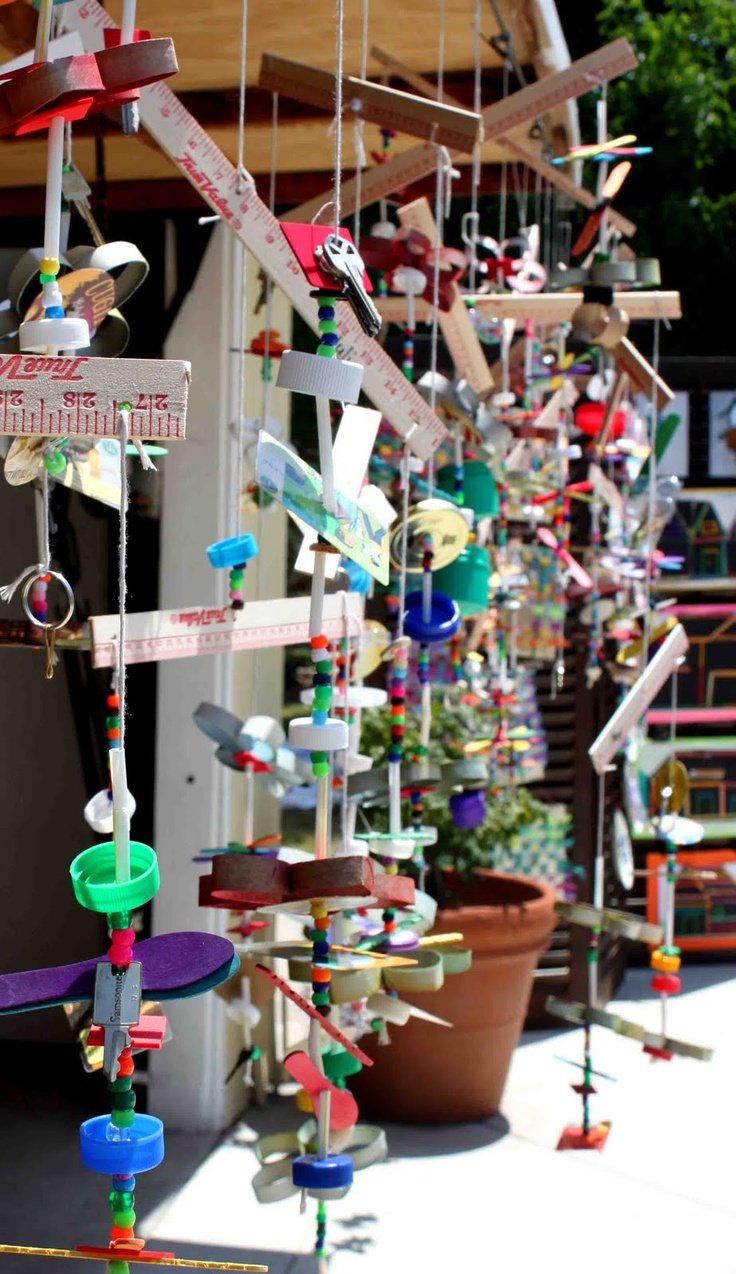 a group of wind chimes hanging from the side of a building next to potted plants