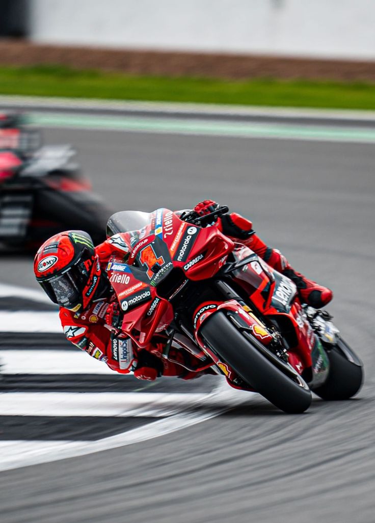 a man riding a motorcycle around a curve on a race track in front of another motorcyclist