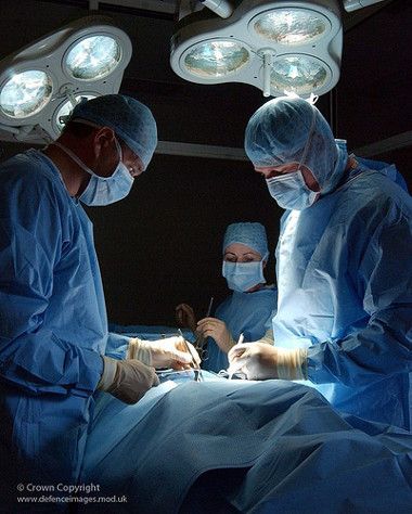 three doctors performing surgery on a patient in an operating room with lights above their heads