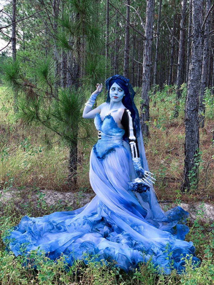 a woman dressed in blue is standing in the woods