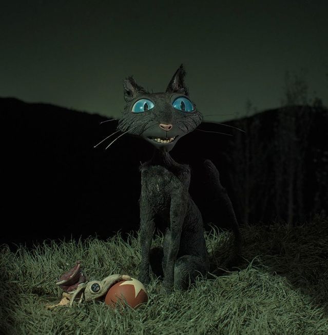 a black cat with blue eyes sitting in the grass