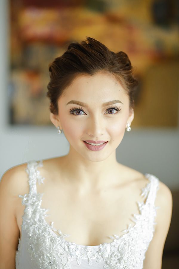 a woman in a wedding dress smiling at the camera with her hair pulled back into a bun