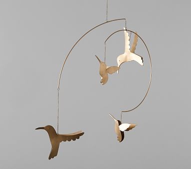 three birds are flying in the air near a circular wind chime that is hanging from it's side