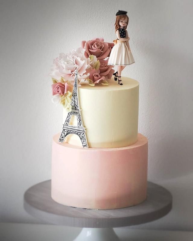 a pink and white cake with an eiffel tower topper on the side