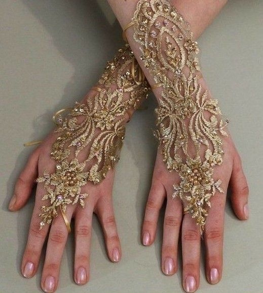 a woman's hands with gold lace and beads on their arms, both holding onto each other