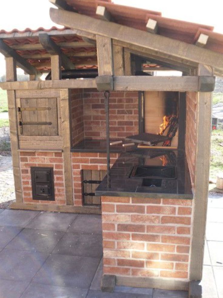 an outdoor oven built into the side of a brick building with a grill on top