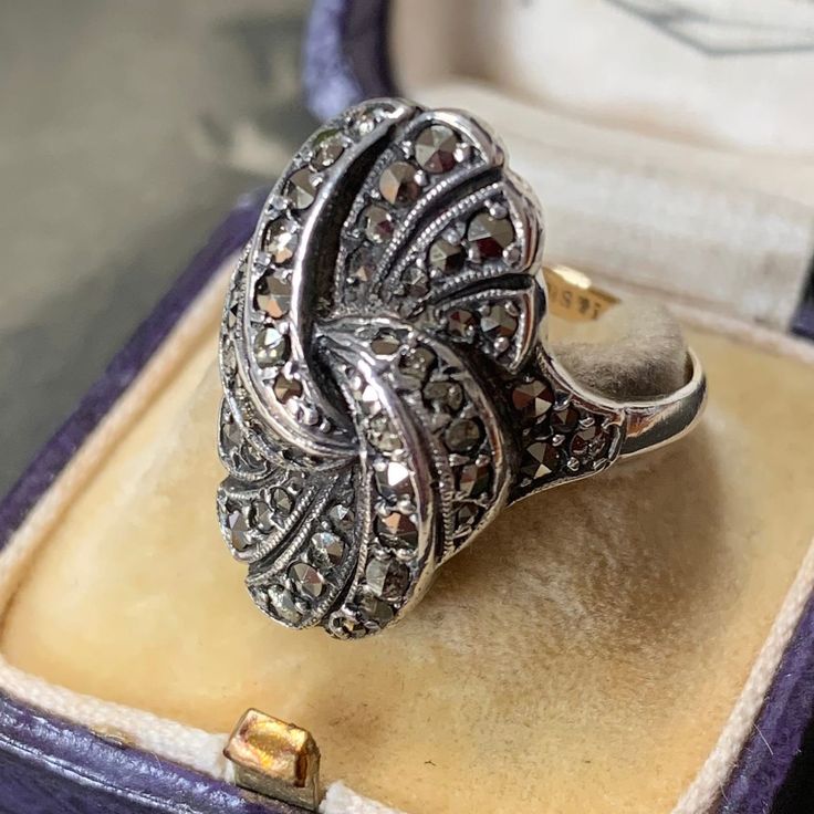 Art Deco era. captivating marcasite cocktail knot ring, a veritable masterpiece from the late 1930s. Size P (UK) or 7.5 US. The ring is crafted from silver, exudes a refined elegance, while the shank, fashioned from 9ct yellow gold, bears the mark 9ct & sil to the inside. Adorned with a remarkable knot style motif, the ring radiates a sense of effortless glamour, evoking the opulence and splendour of its era. Despite the passage of time, this ring retains its inherent beauty, with historic wear Marcasite Ring, Antique Boxes, Knot Ring, Art Deco Era, Swirl Design, Modern Outfits, Antique Jewellery, Ring Ring, Antique Rings