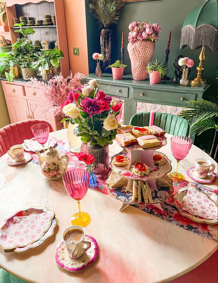 a dining room table with plates, cups and flowers in vases on top of it