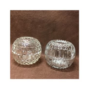 two clear glass dishes sitting on top of a brown cloth covered table next to each other