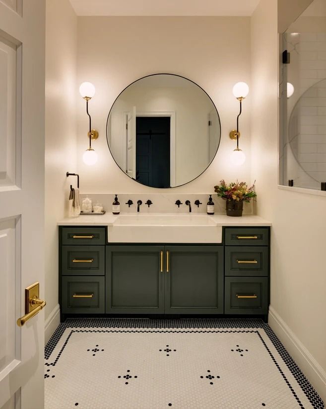 a bathroom with two sinks and a large round mirror above the sink is lit by three lights