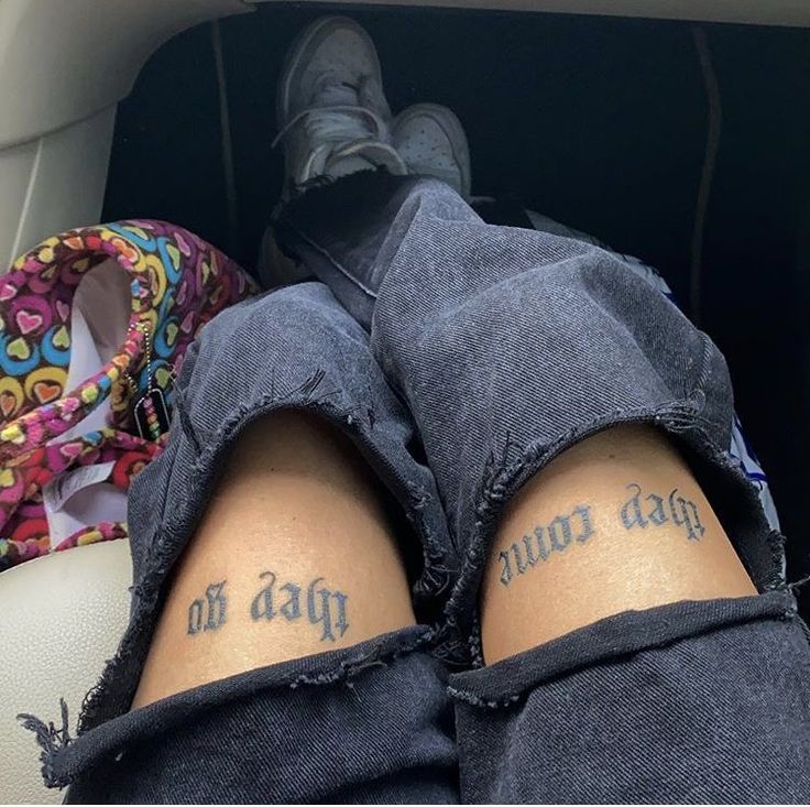 two people with tattoos on their legs sitting in a car