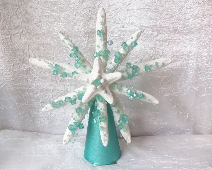 a green vase filled with white snowflakes on top of a white tablecloth