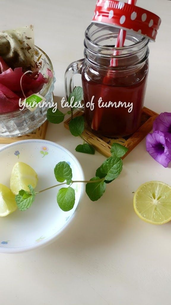 a bowl of lemon slices next to a jar of tea and some flowers on a table