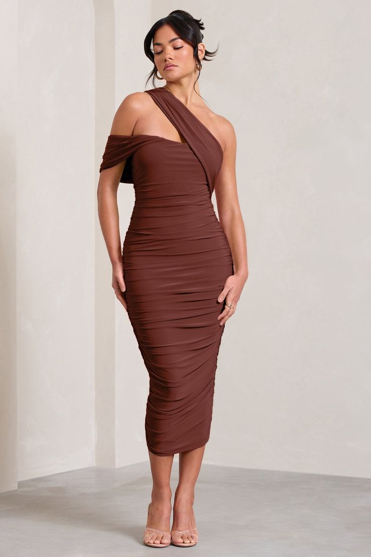 a woman wearing a brown dress with one shoulder draped over her shoulders and heels on the side