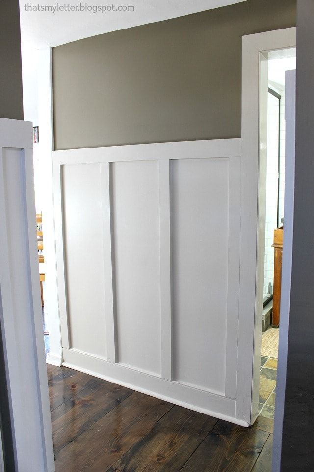 an empty room with white paneling and wood floors