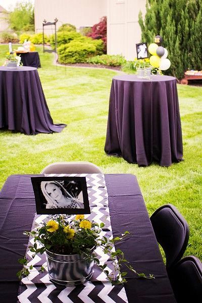 black and white table cloths are set up for an outdoor function in the yard