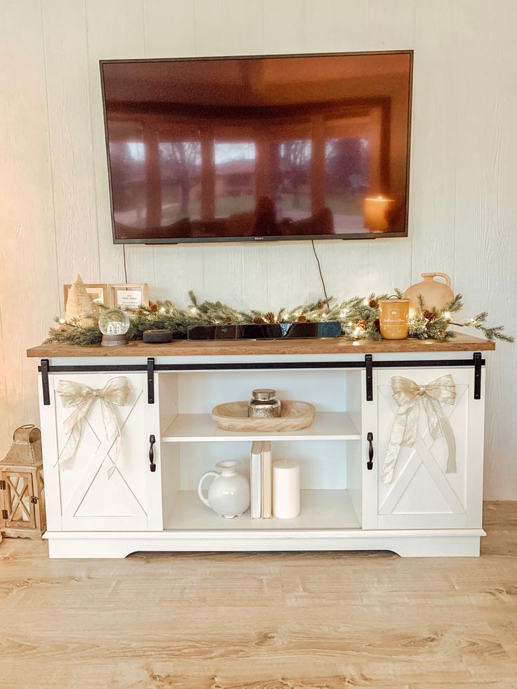 the entertainment center is decorated with greenery and candles