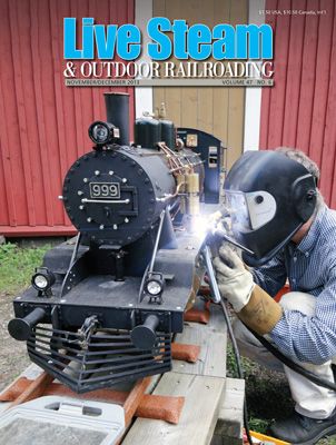 a man working on an old fashioned steam engine in front of a red building with the words live steam and outdoor railroading