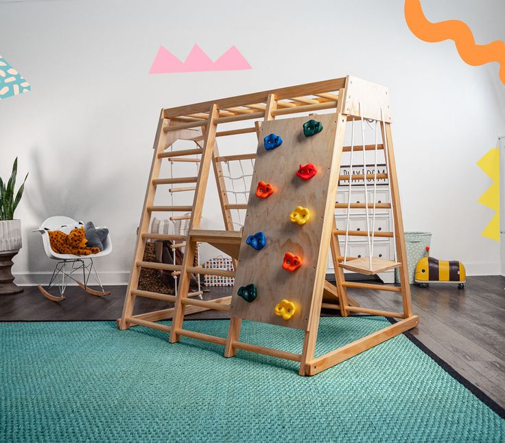 a child's climbing wall in a play room with toys on the floor and walls