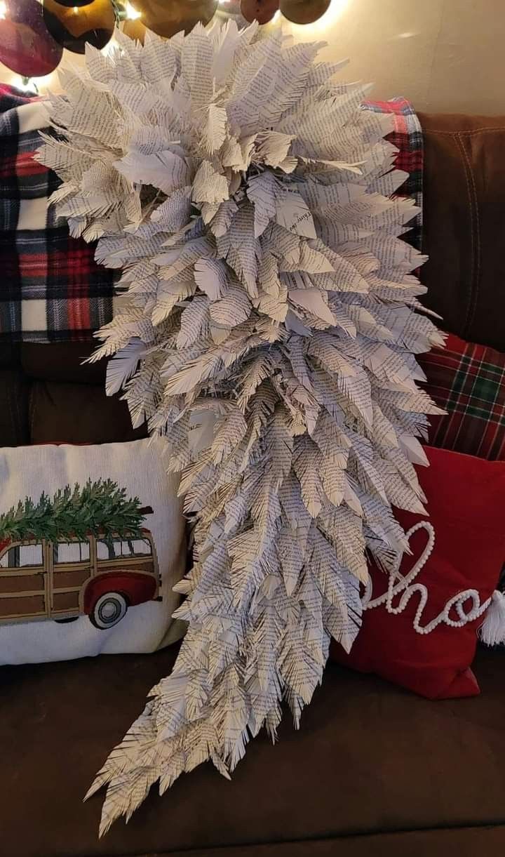 a christmas tree made out of white feathers on top of a brown couch next to pillows