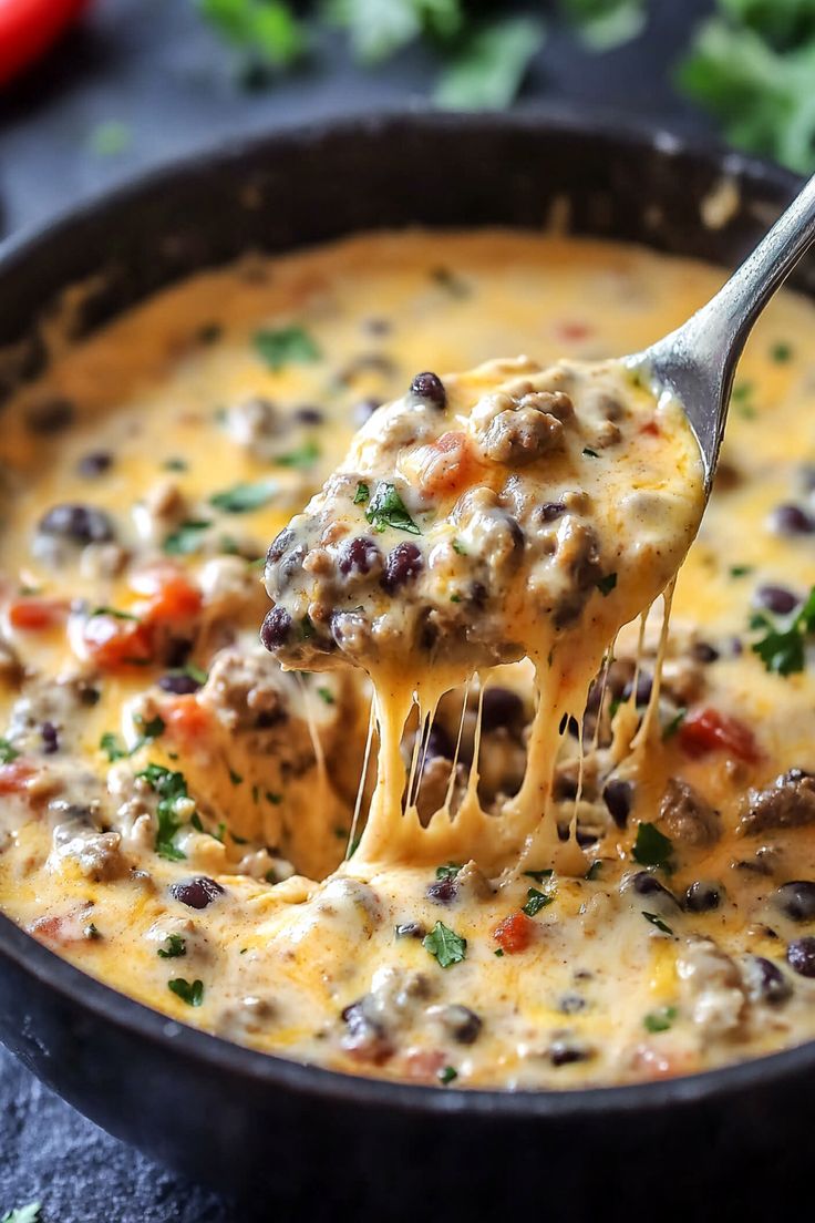 a ladle full of cheeseburger soup being held up by a fork over it