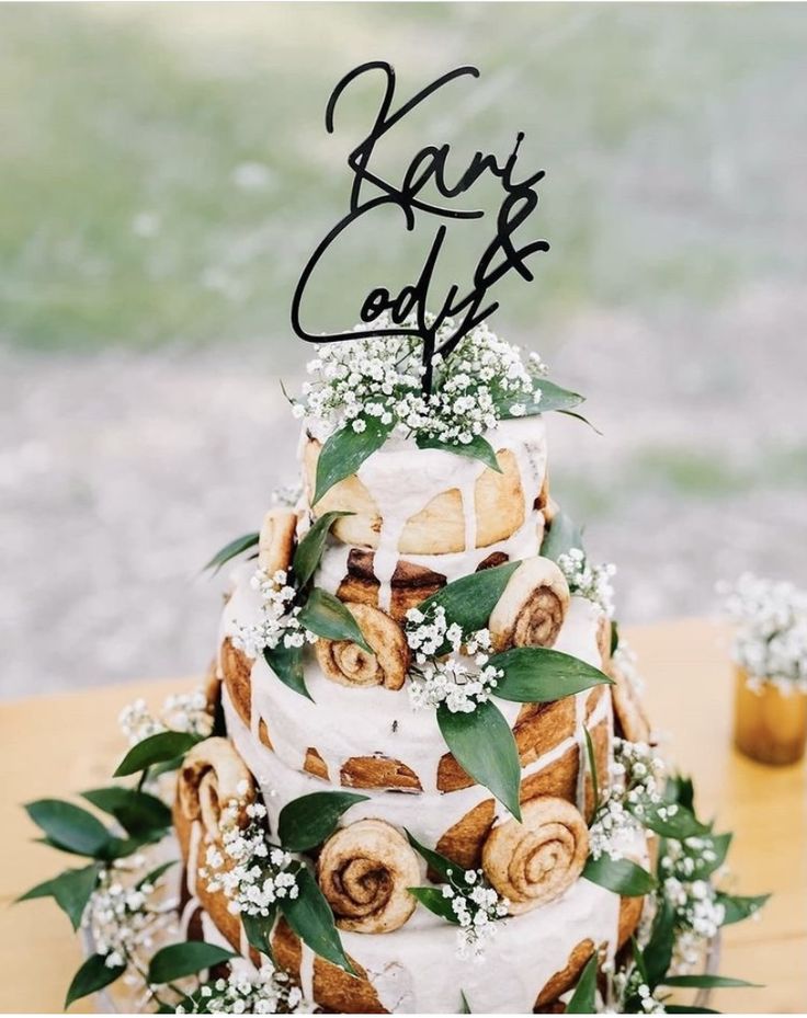 a three tiered cake with flowers and leaves on the top is sitting on a table