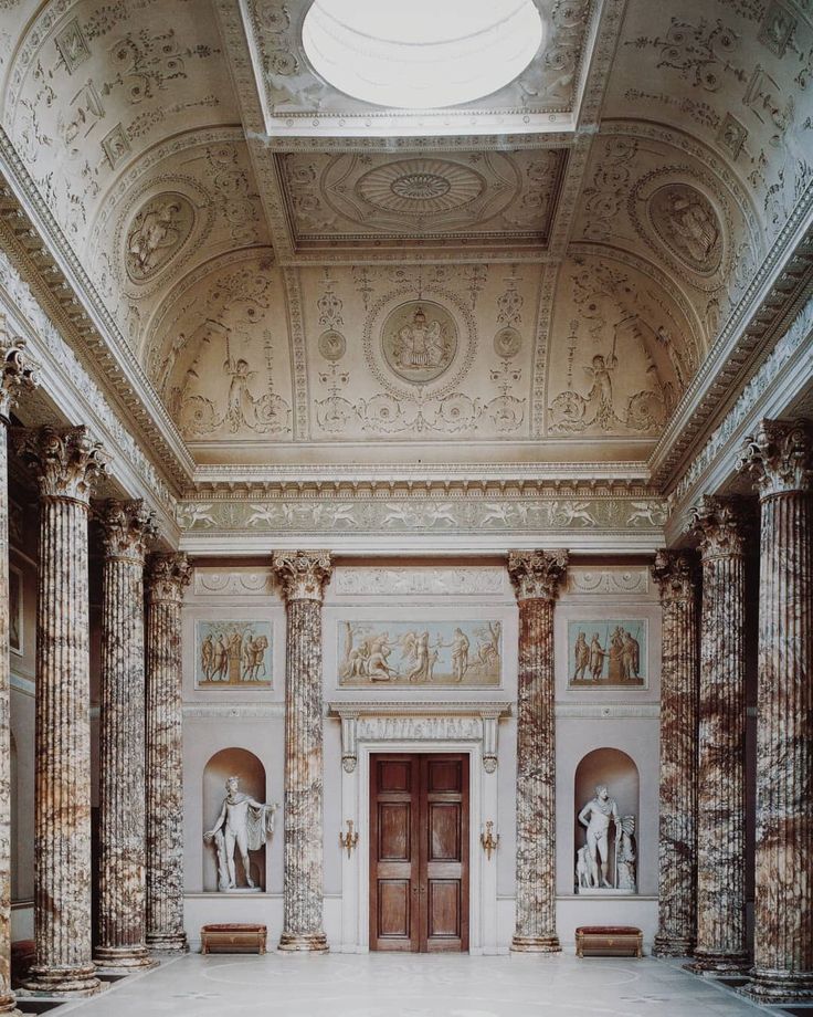 an empty room with columns and paintings on the walls