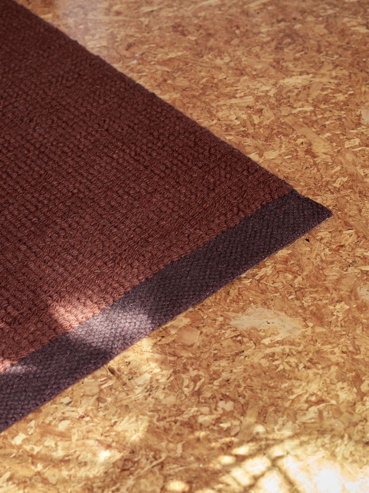 a brown rug sitting on top of a wooden floor next to a white and black cat